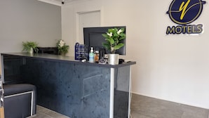 A reception desk with a modern design, a potted plant, a sign for reception, and a logo for 'MOTELS'. - Y Motels Yarraman (Yarraman)