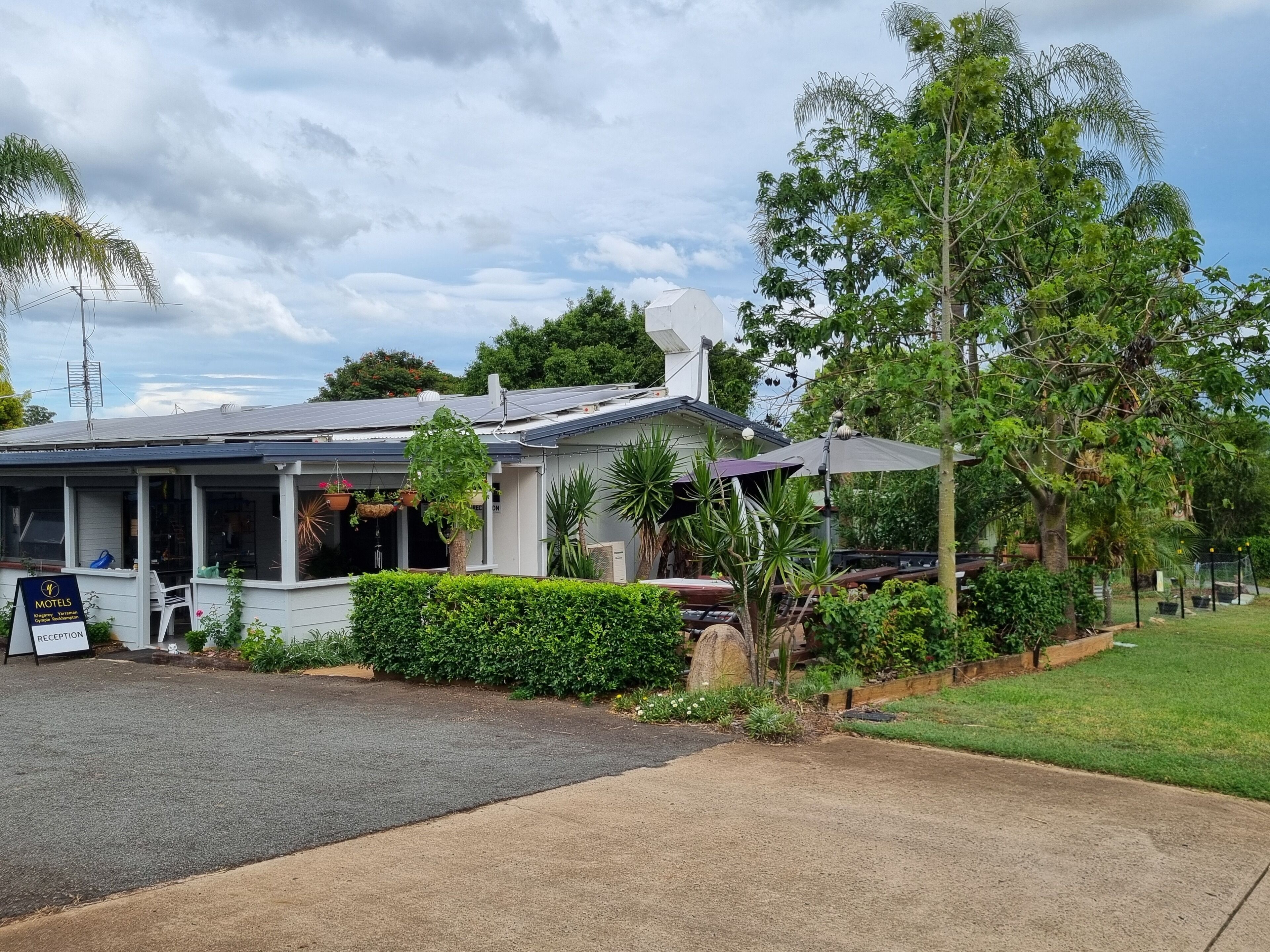 Un motel con zona de recepción, asientos al aire libre y un jardín bien cuidado.