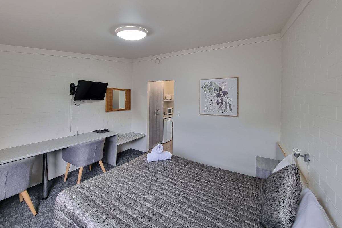 A compact room with a bed, a desk, and a chair.