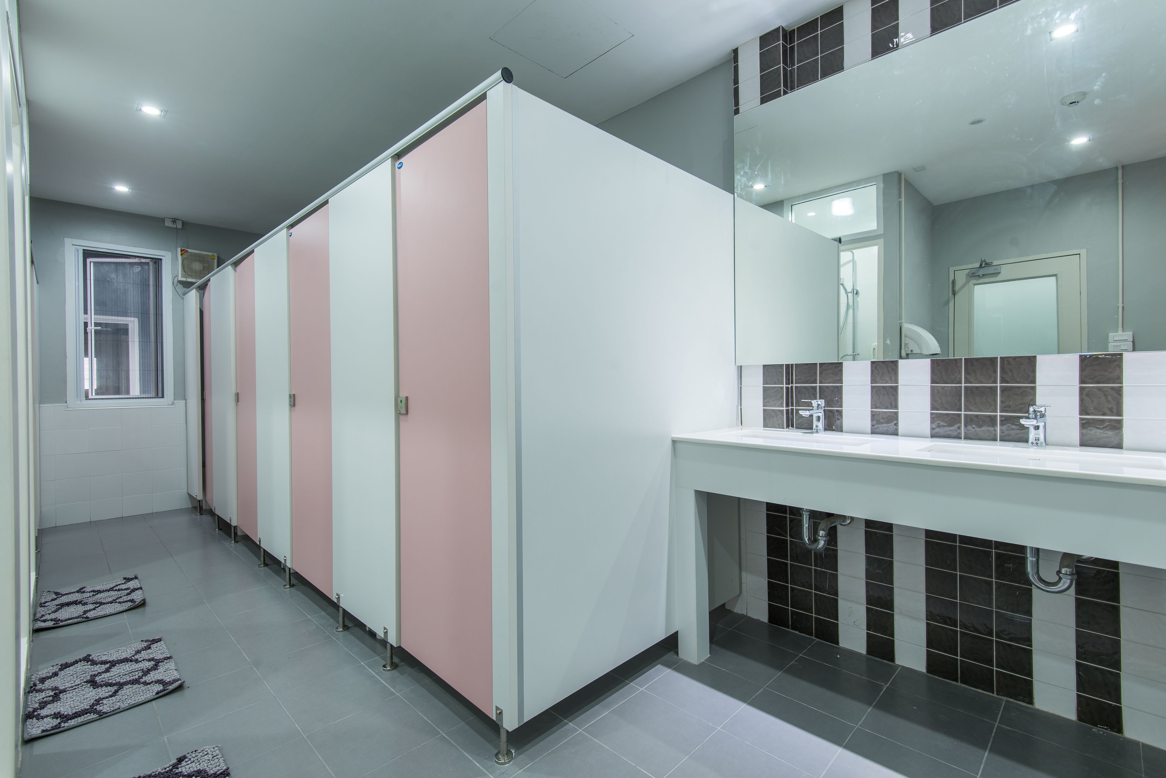 A modern bathroom with a long row of lockers, a large mirror, and a sink area.