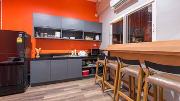 Una cocina moderna con armarios grises, un refrigerador negro y una barra de madera con taburetes de bar.