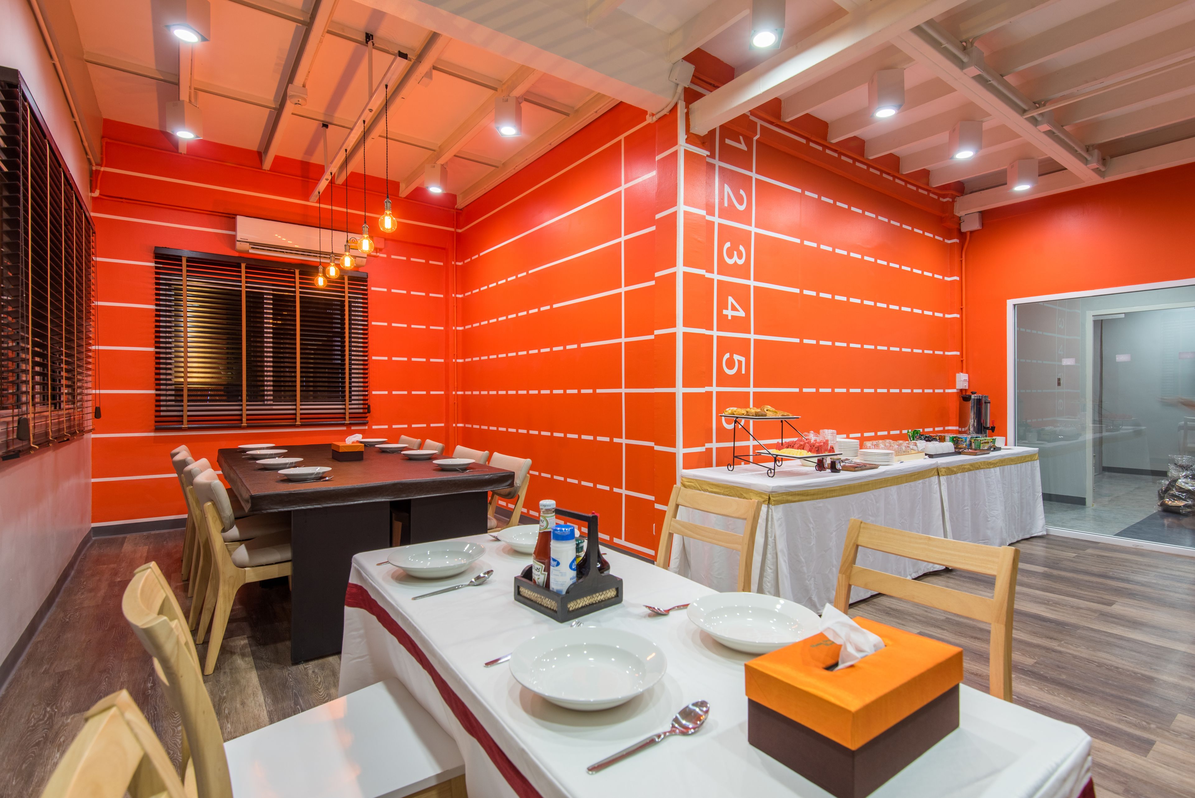 Un salón de conferencias con una larga mesa dispuesta para una reunión, equipado con platos, cubiertos y una botella de agua.