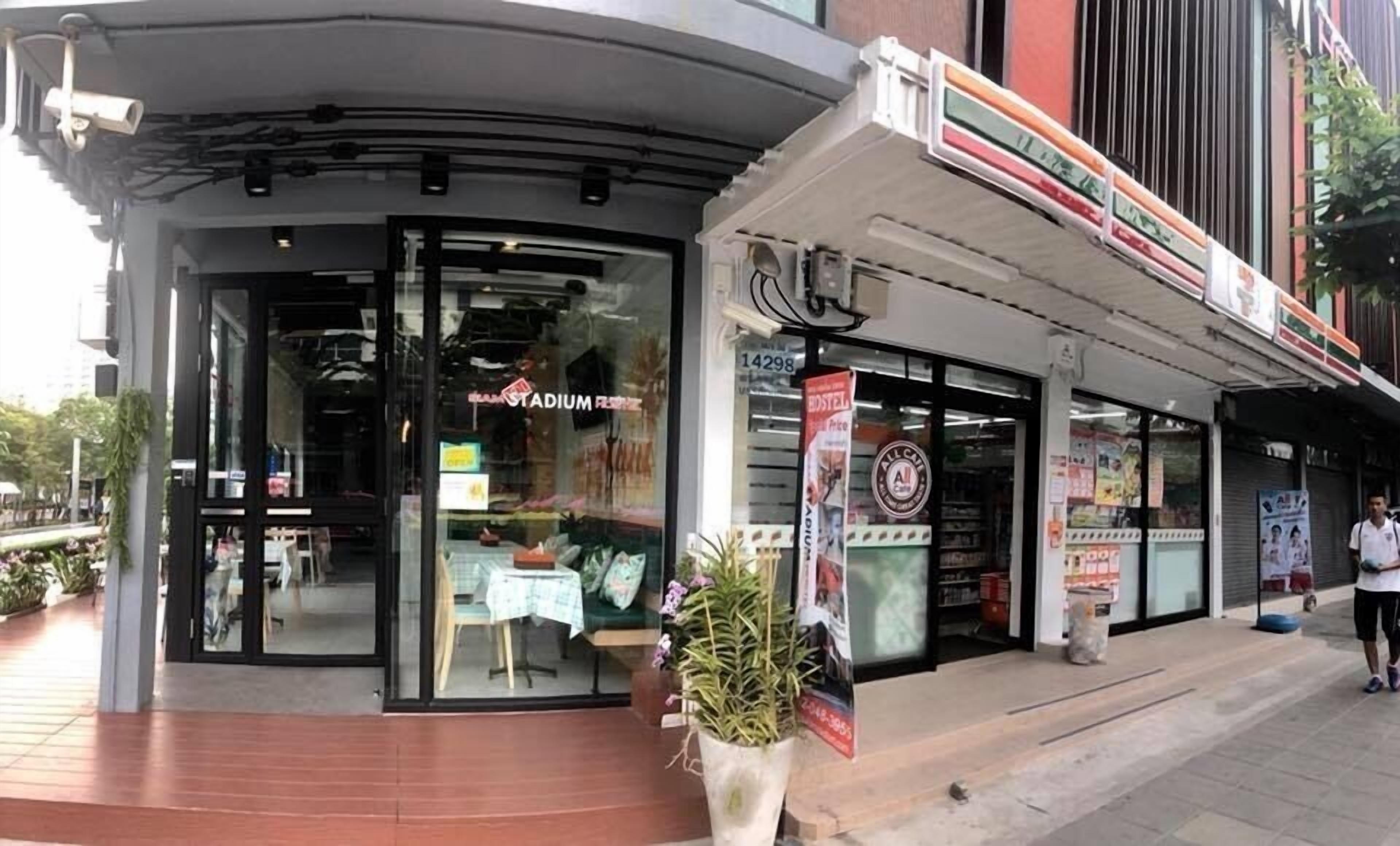 A storefront with a glass door, a sign reading "STADIUM FOOD," and a potted plant in front.
