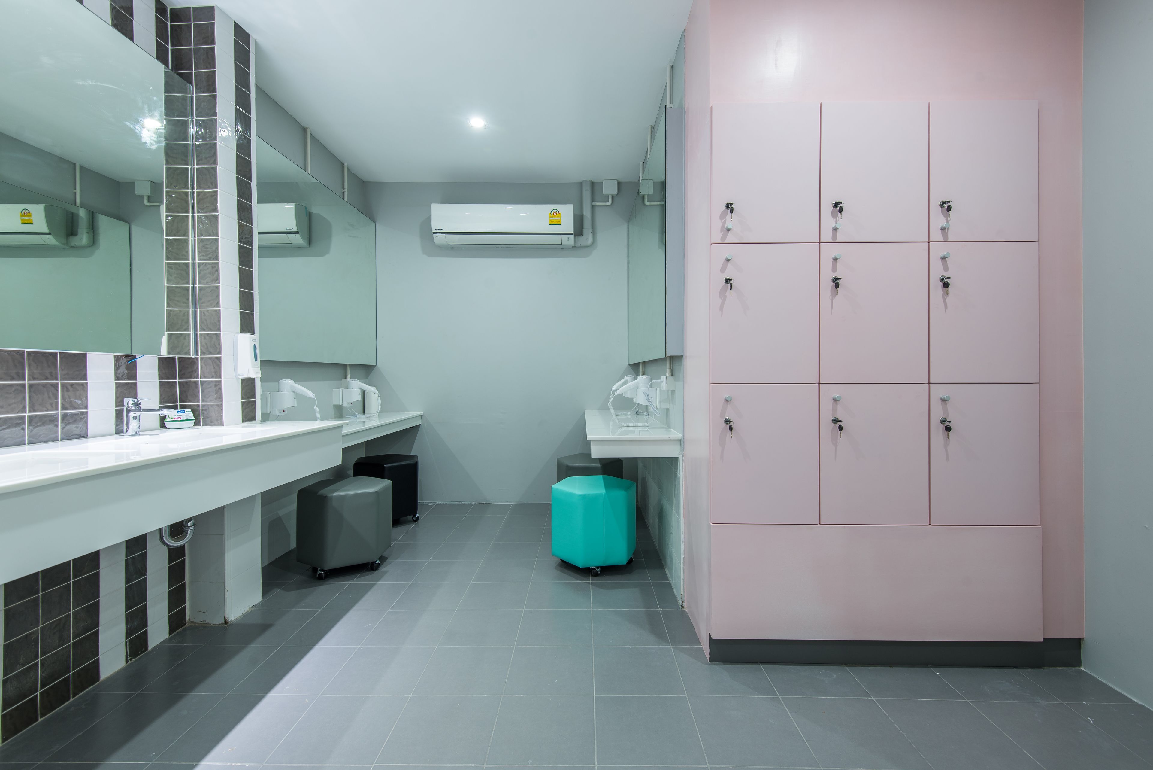 A modern bathroom with a large mirror, a sink, a toilet, and a storage cabinet.