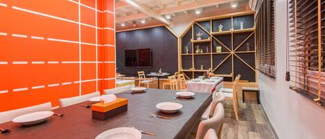 A modern dining area with a long table set for a meal, surrounded by chairs.