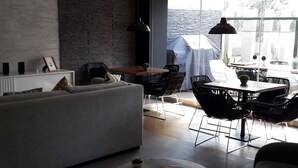 A modern living room with a sofa, coffee table, and chairs, a dining area with a table and chairs, and a large window with a view of the outdoors. - APARTMENT IN THE HEART MIRAFLORES (Miraflores)