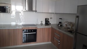 A modern kitchen with stainless steel appliances, wooden cabinets, and a granite countertop. - APARTMENT IN THE HEART MIRAFLORES (Miraflores)