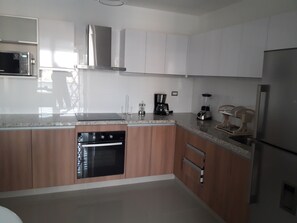 A modern kitchen with stainless steel appliances, wooden cabinets, and a granite countertop.