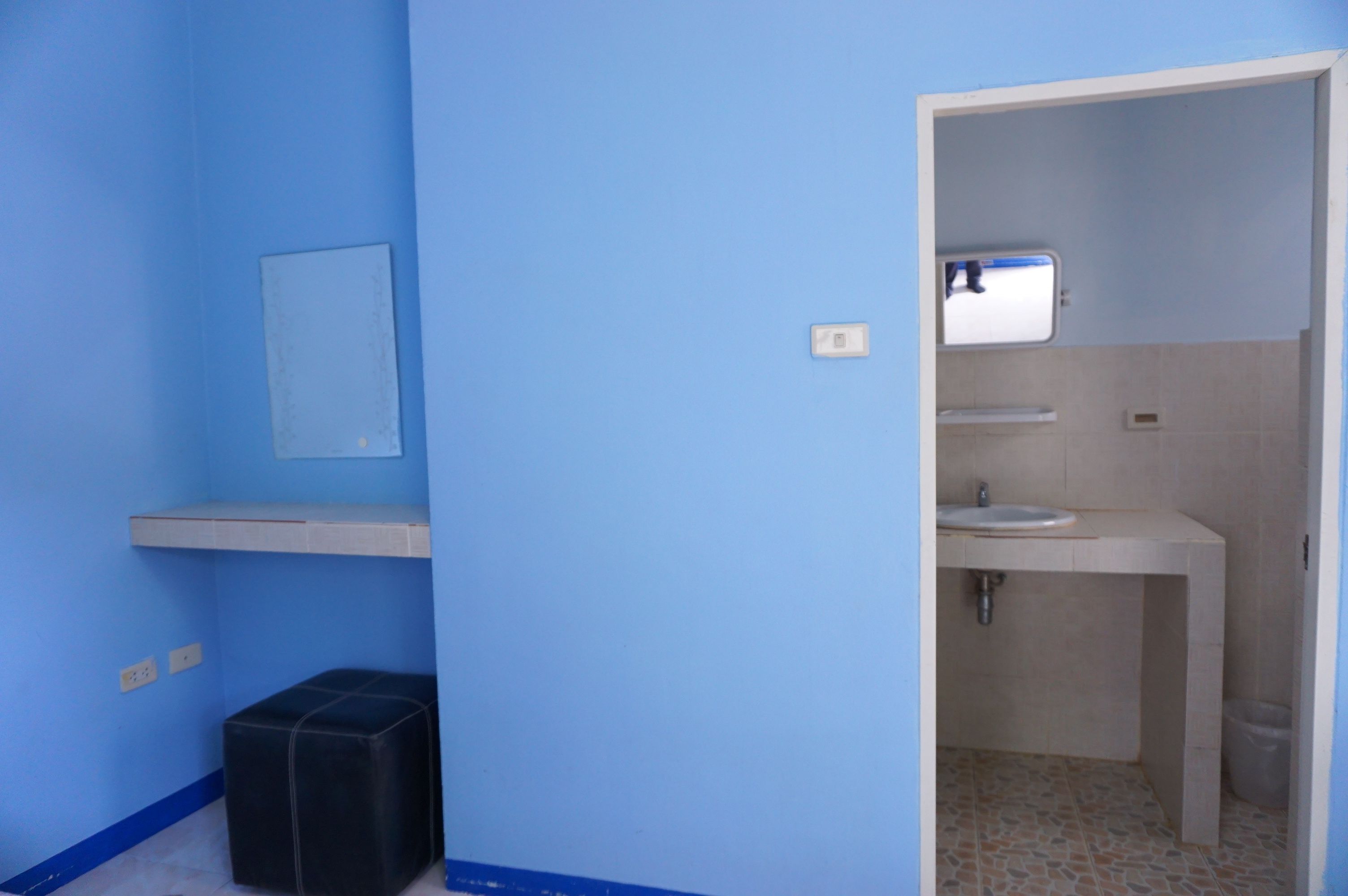 A small bathroom with a sink, mirror, and a trash bin.