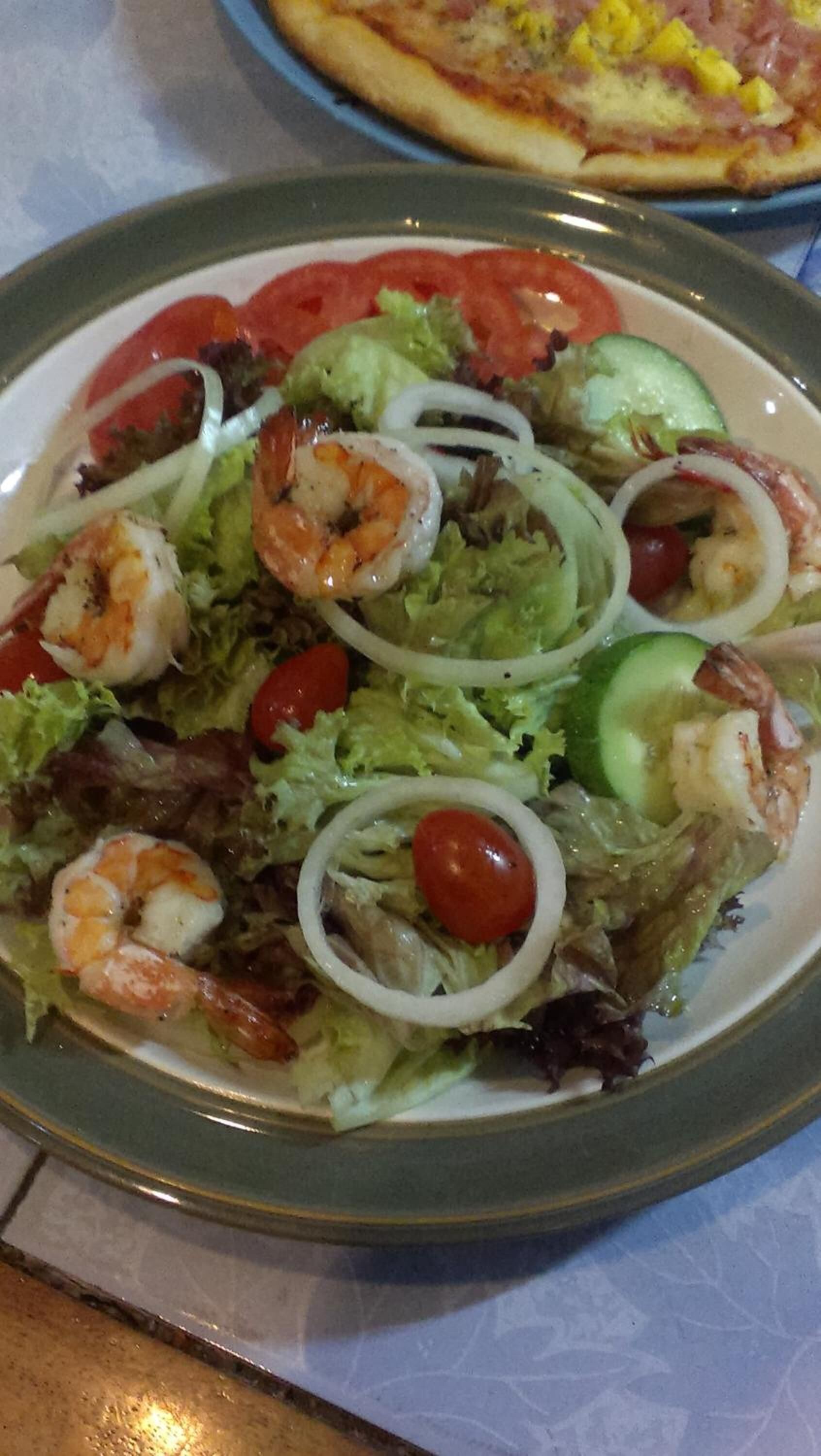 A plate of shrimp salad with lettuce, tomatoes, and cucumbers.