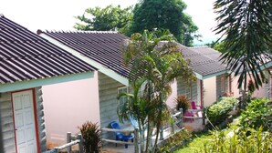 A row of small, single-story buildings with tiled roofs, surrounded by lush greenery and a well-maintained garden. - Dahla House Ranong (Ranong)