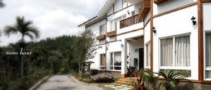Stroll up to the charming entrance, where a cozy porch awaits with a bench and lush greenery surrounding the property.