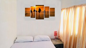 A hotel room with a bed, white pillows, a wall-mounted artwork depicting a sunset scene, a red lamp, and beige curtains. - Mount view 11 (Kandy)