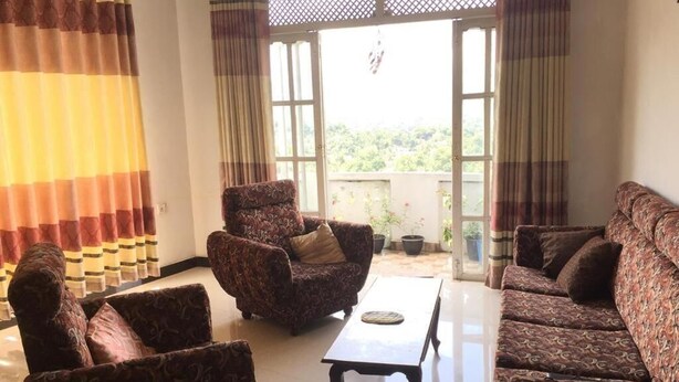 A living room with patterned sofas, a coffee table, and curtains. - Mount view 11 (Kandy)