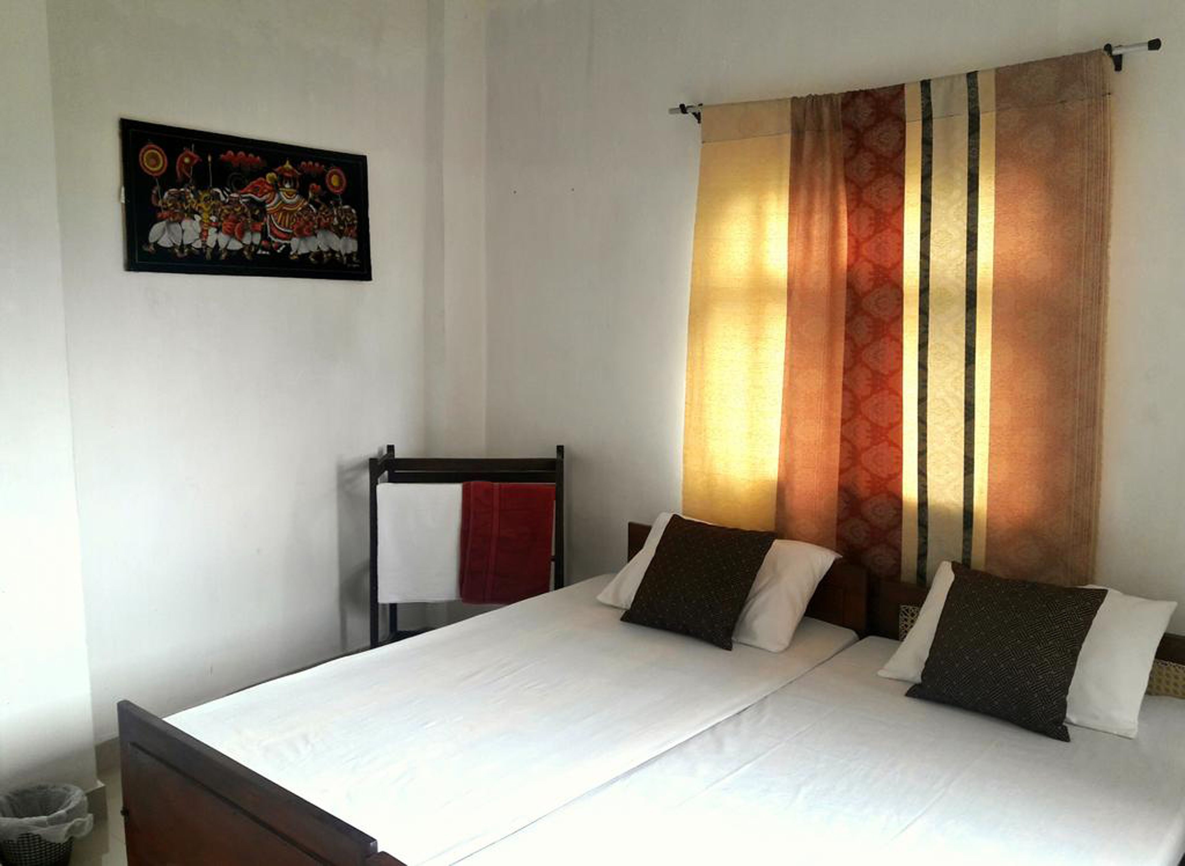 Une chambre d’hôtel avec un lit, une serviette rouge et un tableau accroché au mur.