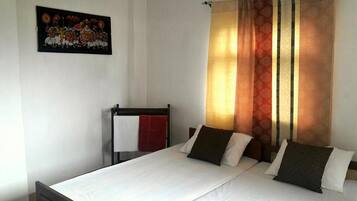 Une chambre d’hôtel avec un lit, une serviette rouge et un tableau accroché au mur.