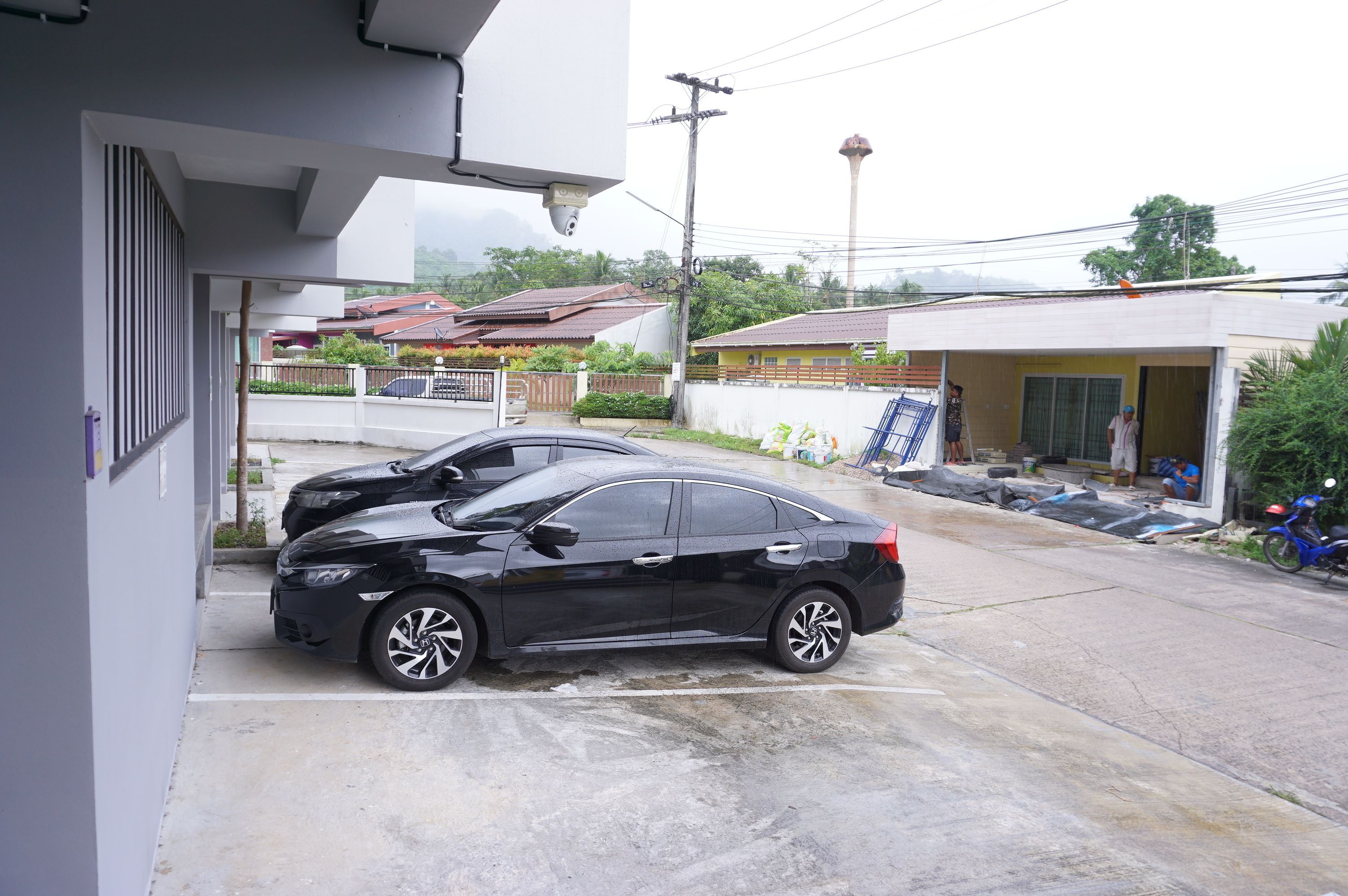 Un coche negro estacionado en una entrada de casa con una vivienda al fondo.