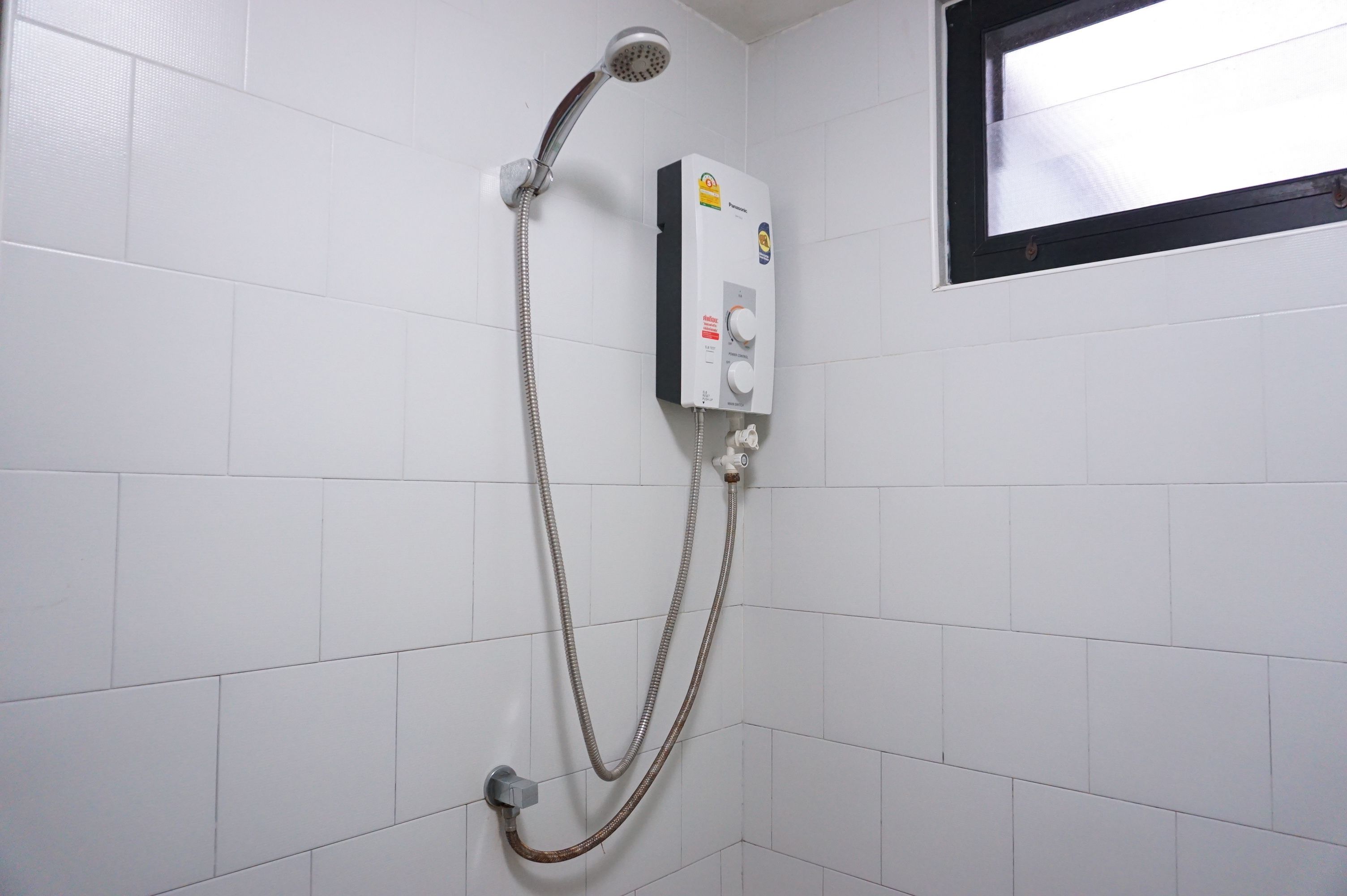 A shower with a control panel and a window above it.