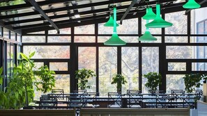 A restaurant with a modern interior, featuring a glass ceiling, green pendant lights, and multiple seating areas with tables and chairs. - Muju Nabom Resort (Muju)