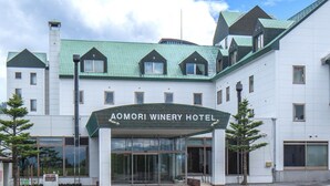 The exterior of Aomori Winery Hotel with a green roof and a covered entrance.