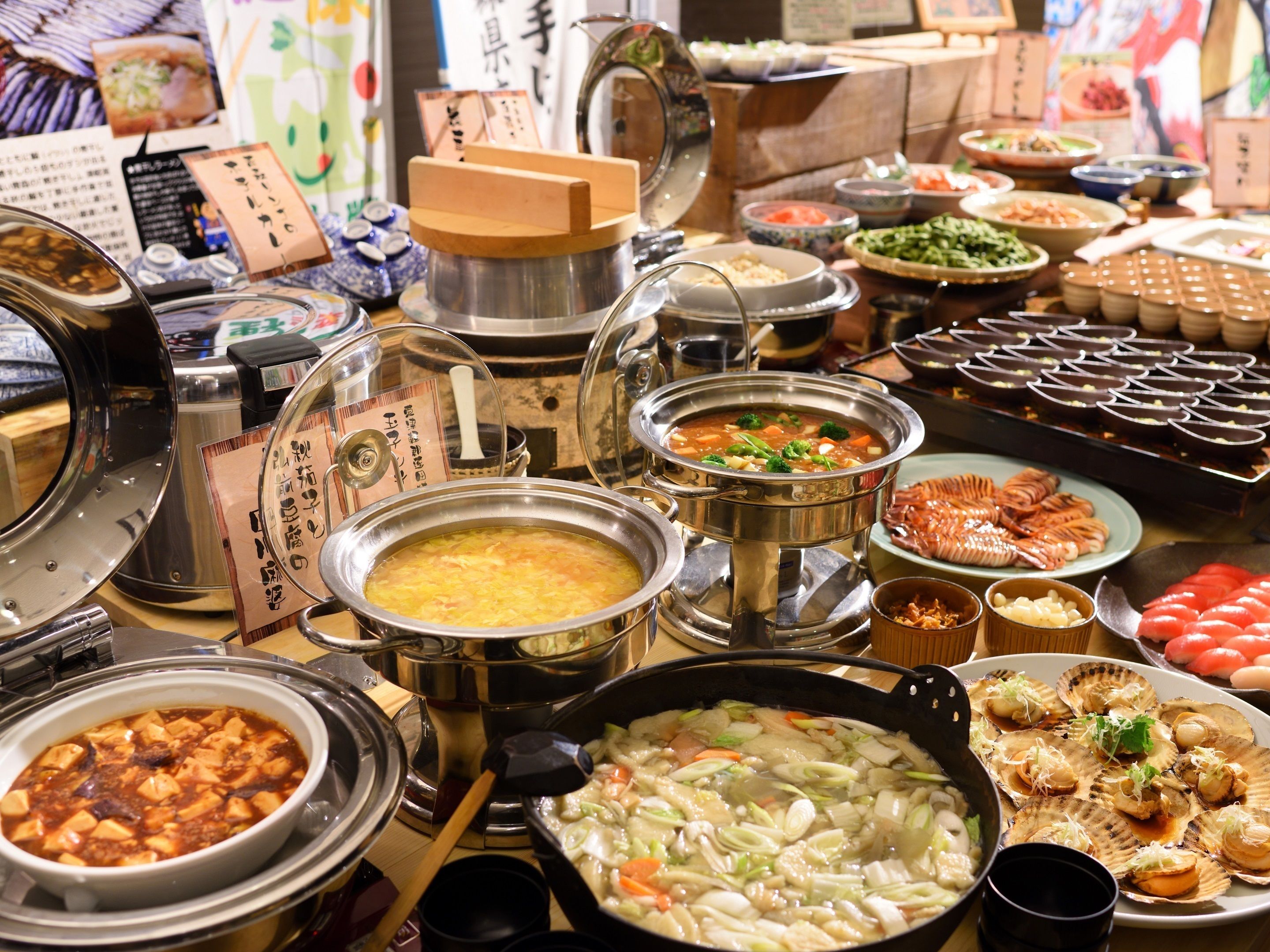 A buffet with various dishes including soups, vegetables, and seafood.