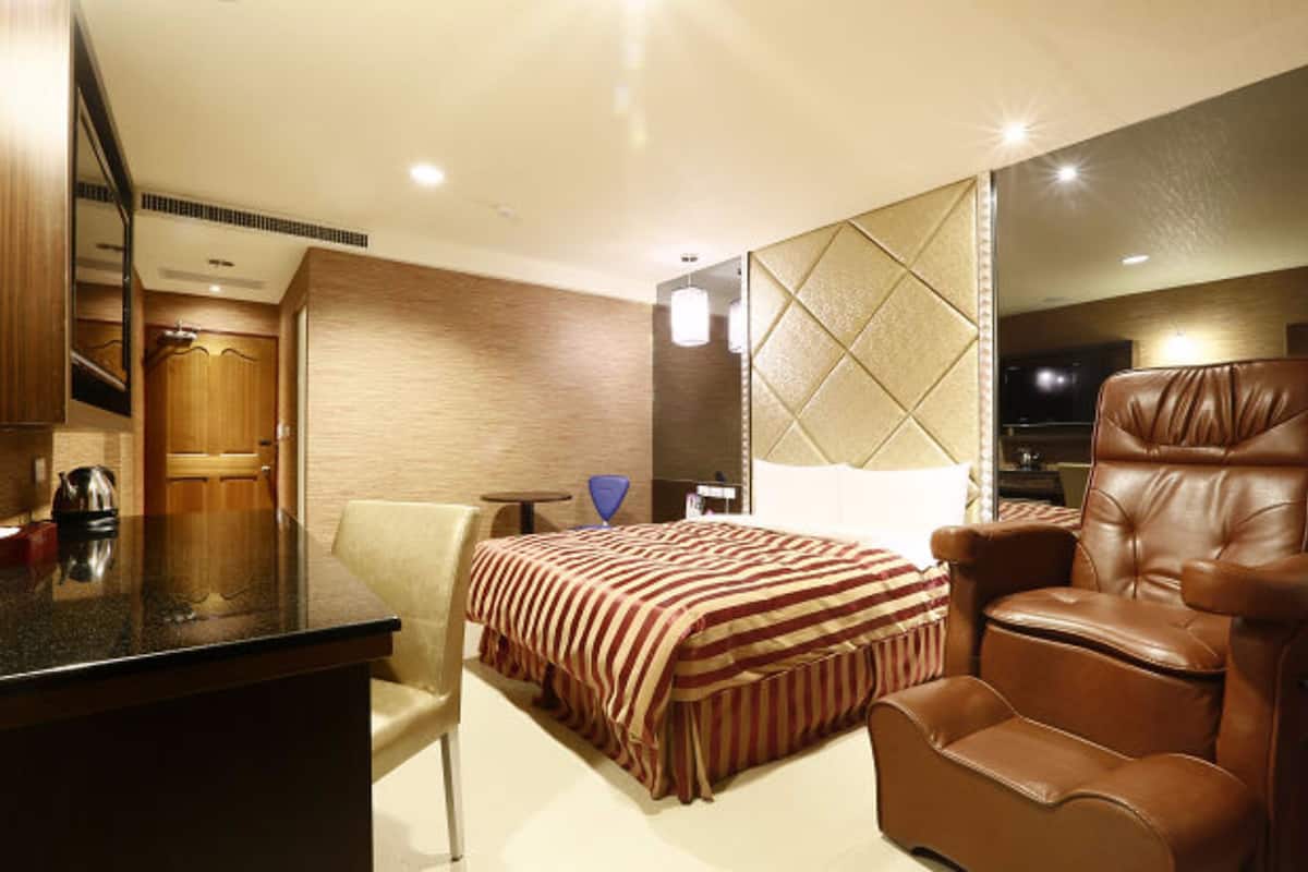 Ein Hotelzimmer mit einem Bett, einem Ledersessel, einem Schreibtisch mit Wasserkocher und einem Fernseher.