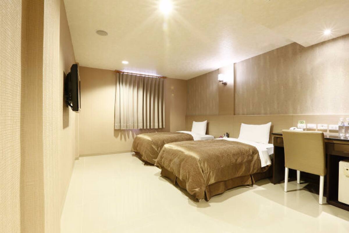 Ein Hotelzimmer mit zwei Betten, einem Schreibtisch und einem Stuhl.