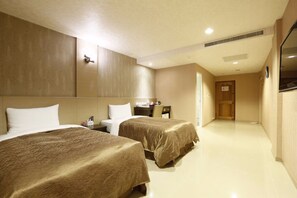 Ein Hotelzimmer mit zwei Betten, einem Schreibtisch und einem Fernseher.