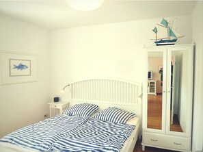 Une chambre à coucher avec un lit, une table de chevet, un miroir et une décoration maritime au mur.