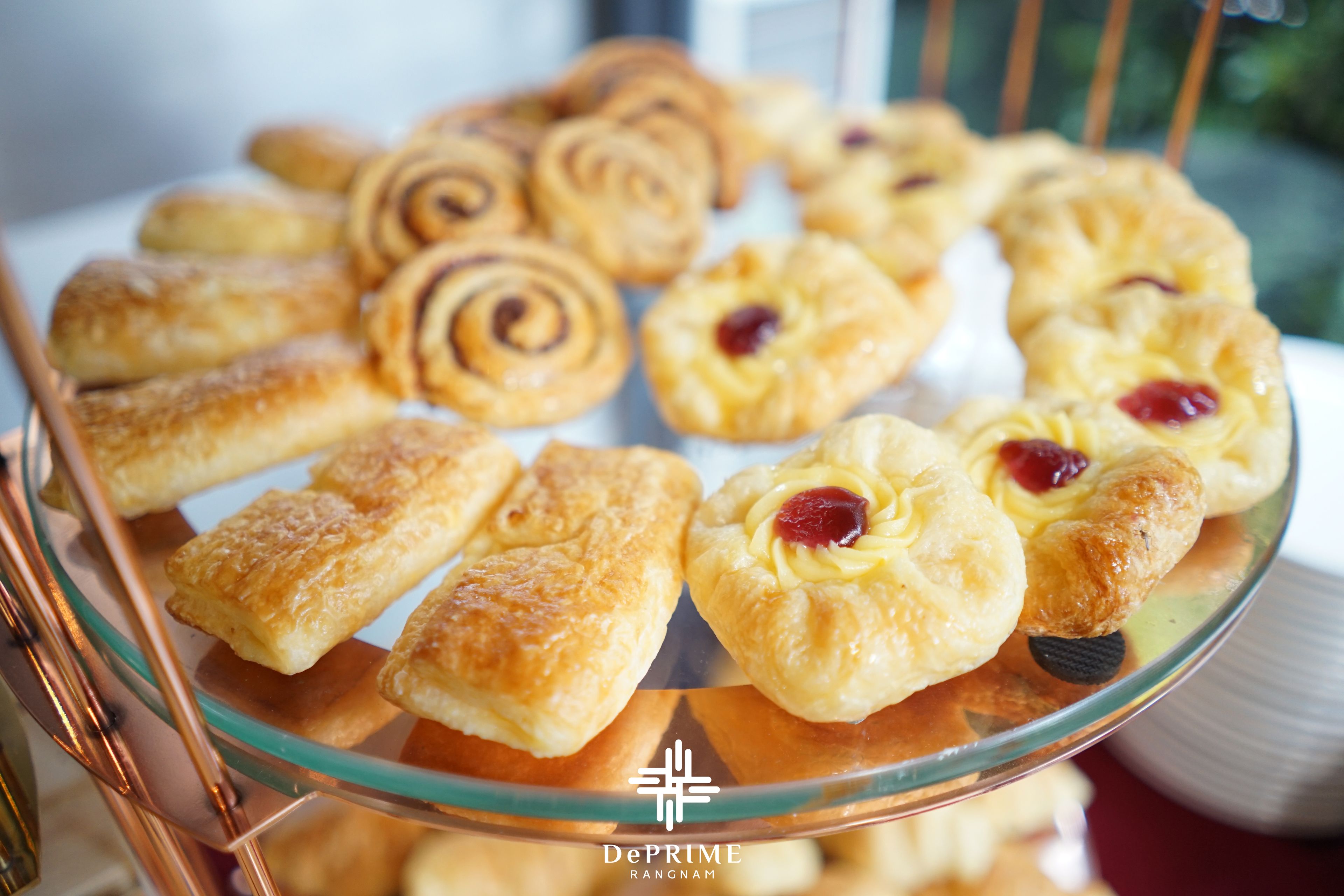 A glass display case with various pastries, including croissants and pastries with fruit toppings.