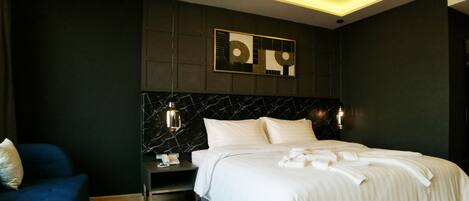 A modern hotel room with a marble headboard, a bedside table with a phone, and a blue sofa.
