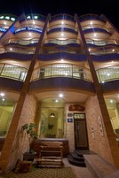 Un hotel de varios pisos con diseño moderno, que cuenta con balcones y una entrada central con escalones.
