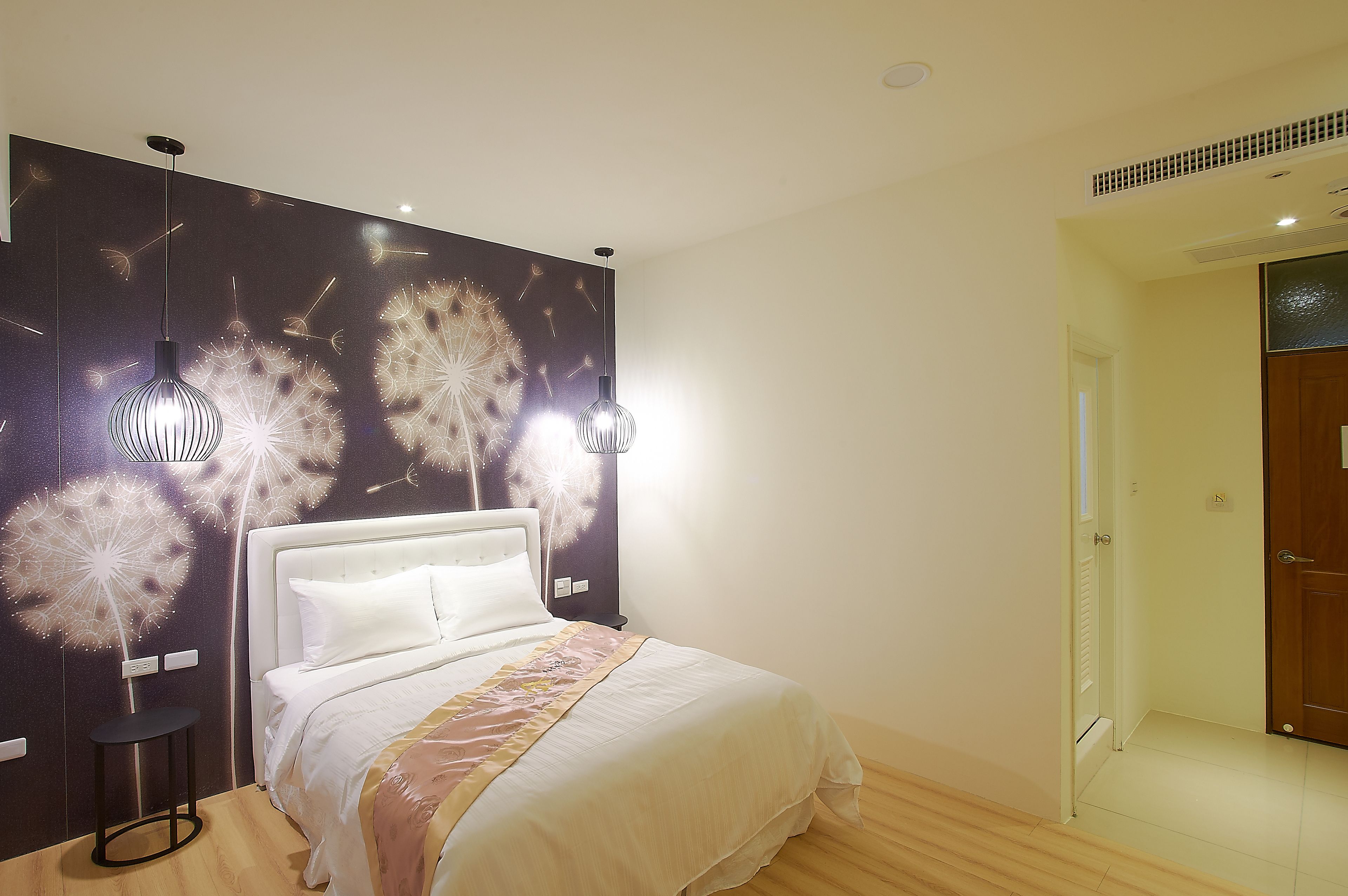 Un dormitorio con una cama, una mesita de noche, una lámpara de pared y una puerta.