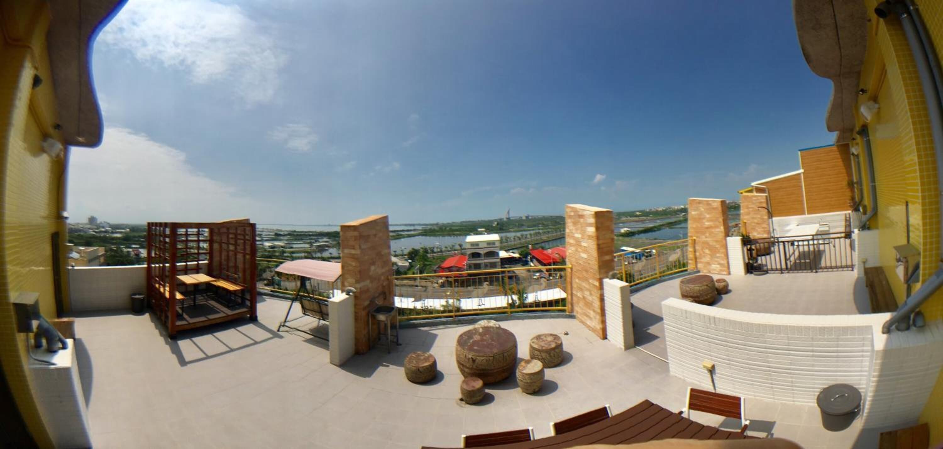 A rooftop terrace with outdoor seating, stone pillars, and a view of the cityscape.