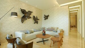 Una sala de estar moderna con un sofá blanco, una mesa de centro redonda y decoración de mariposas en la pared.
