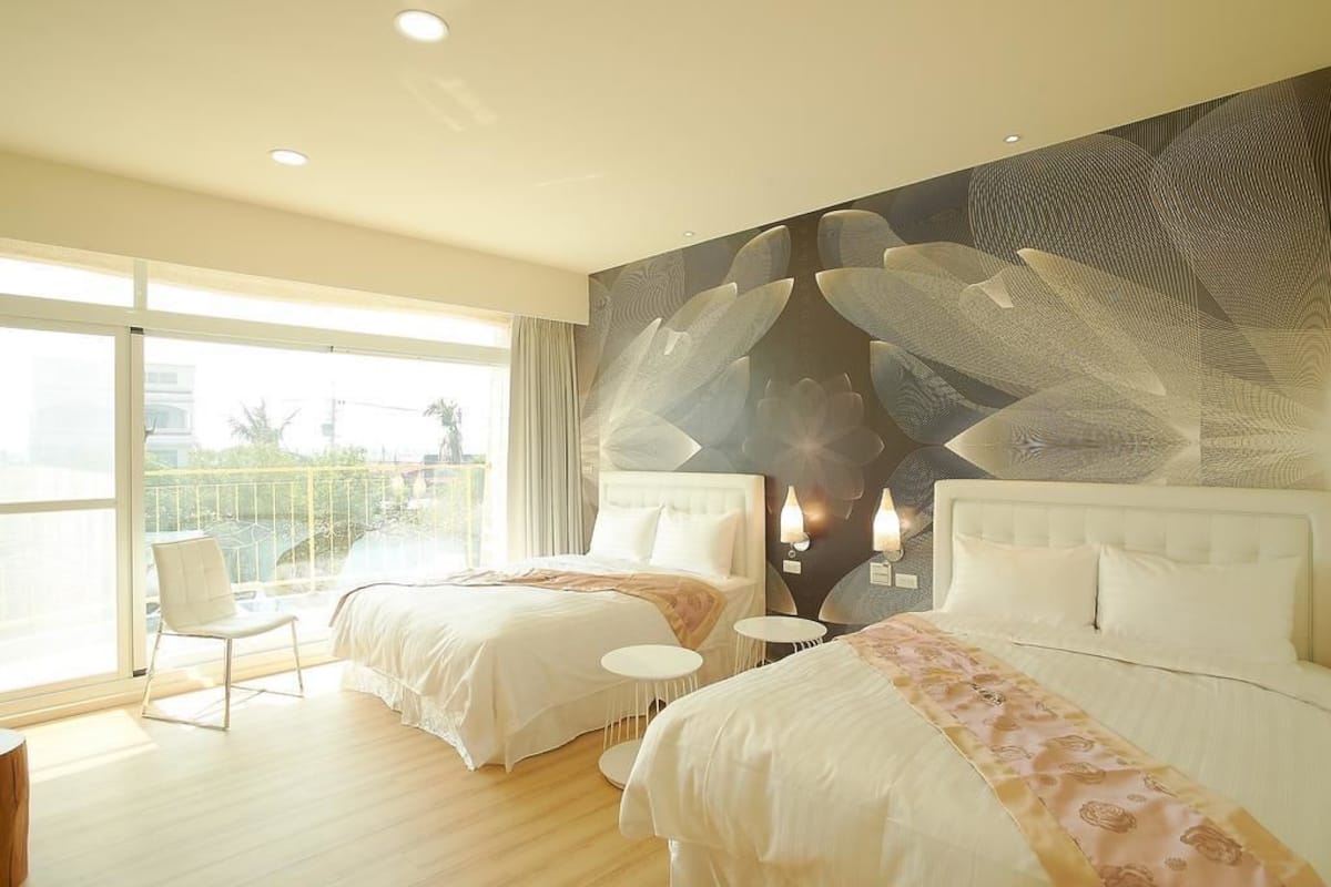 A hotel room with two beds, a large window, and a balcony.