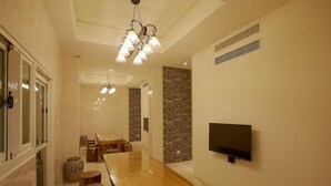 Un comedor moderno con una larga mesa de madera, un televisor montado en la pared y una pared de acento de piedra.