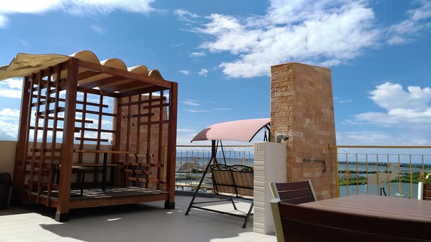 Una terraza con una pérgola de madera, un sillón mecededor y una chimenea de ladrillo.