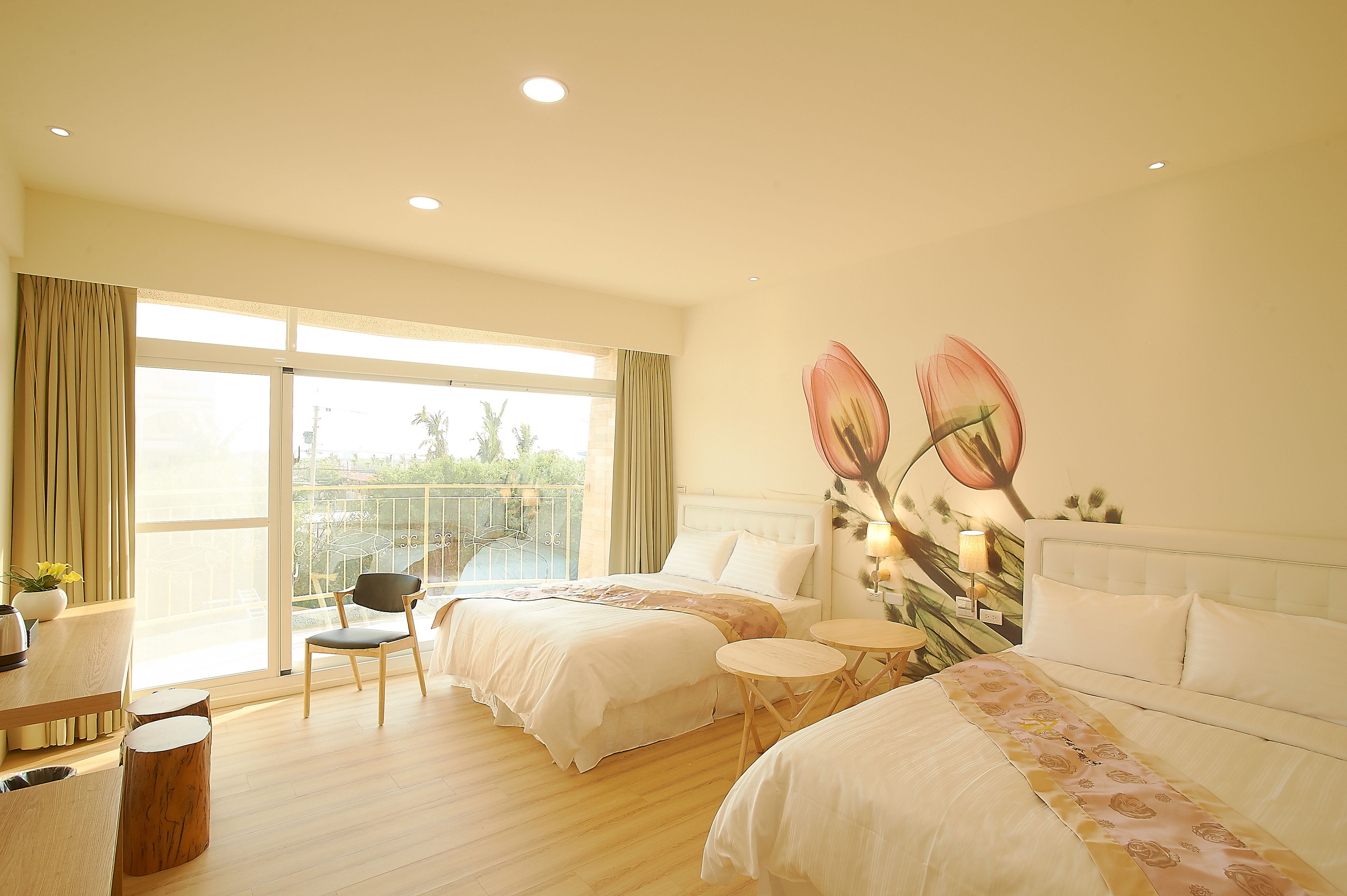A hotel room with two beds, a dining area, and a balcony with a view.
