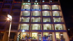 Un hotel de varios pisos con balcones identificados y una entrada bien iluminada.