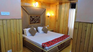 Een kamer met houten lambrisering, een bed, een wandlamp en een stopcontact.