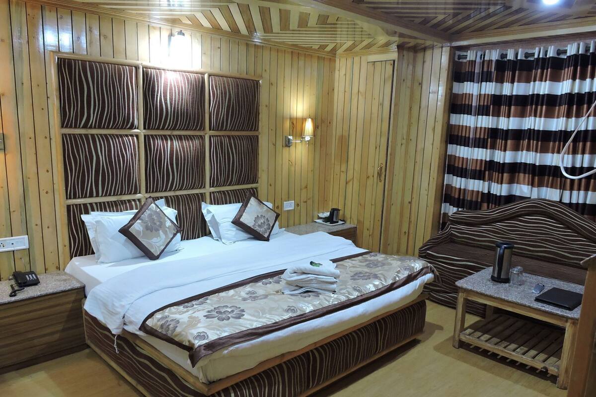 A wooden-paneled room with a bed, bedside table, and a wall-mounted lamp.