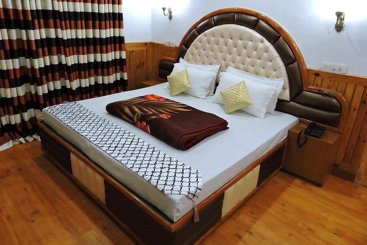 A hotel room with a bed, wooden headboard, white bedding, and a striped curtain.