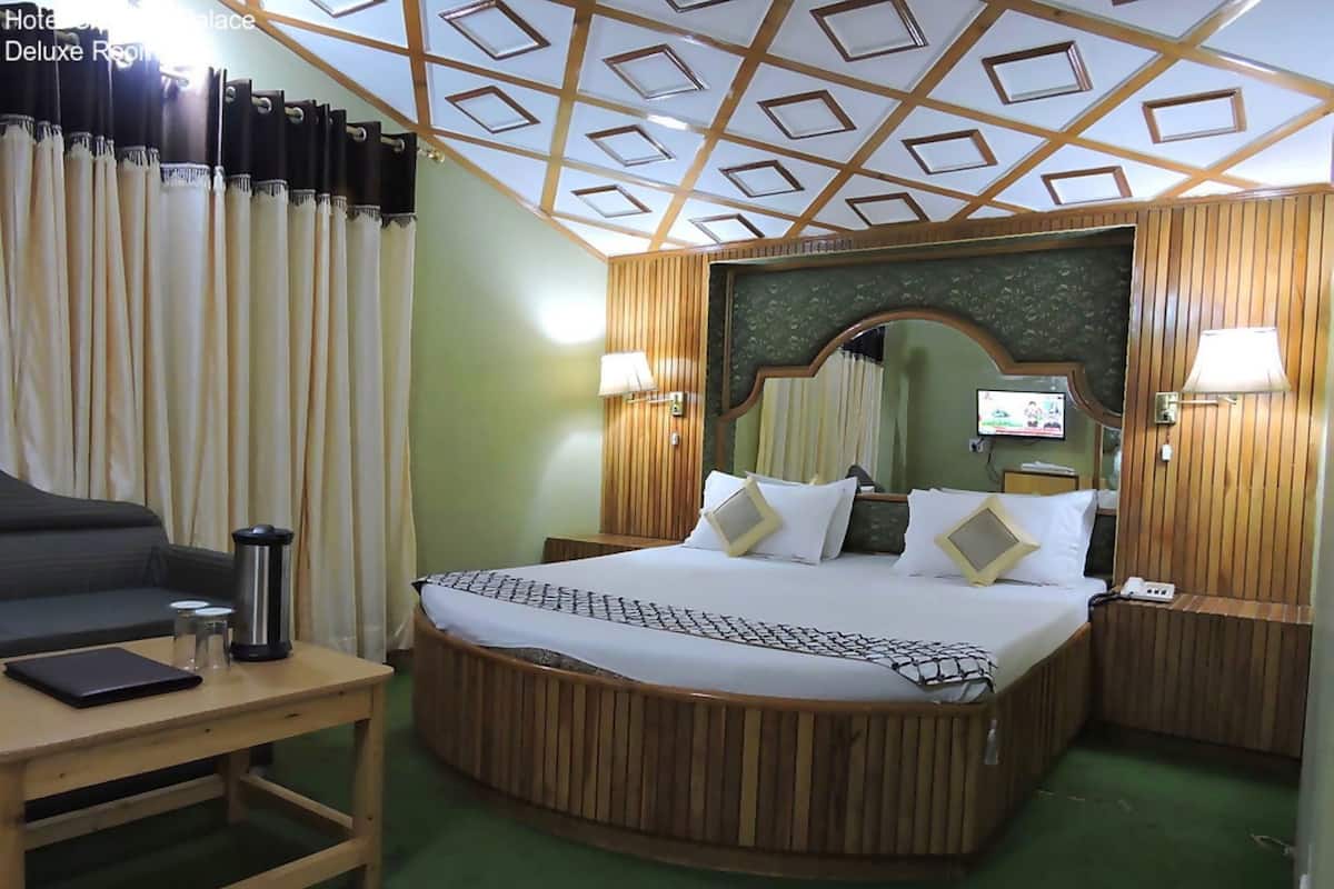 A hotel room with a round bed, a desk, a chair, and a television.