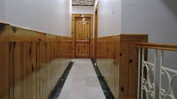 A hallway with wooden paneling, a marble floor, and a wooden door at the end.