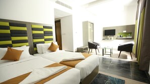 A hotel room with two beds, a TV, a small table, and a chair. - Hotel Jump In & Out (Coimbatore)
