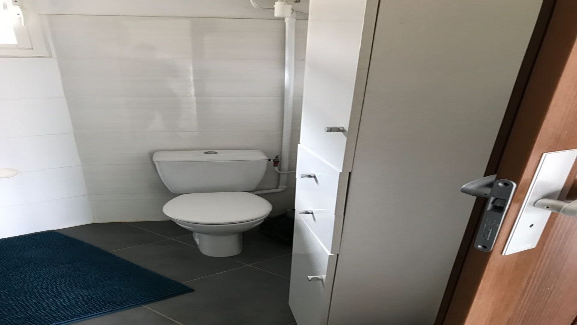 A small, compact bathroom with a toilet, a sink, and a shower stall.