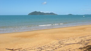 A beach with a sandy shore, calm sea, and a distant island. - Banfields Retreat (Wongaling Beach)
