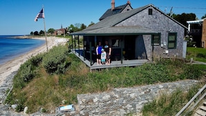 Een huis met veranda, met uitzicht op een strand.