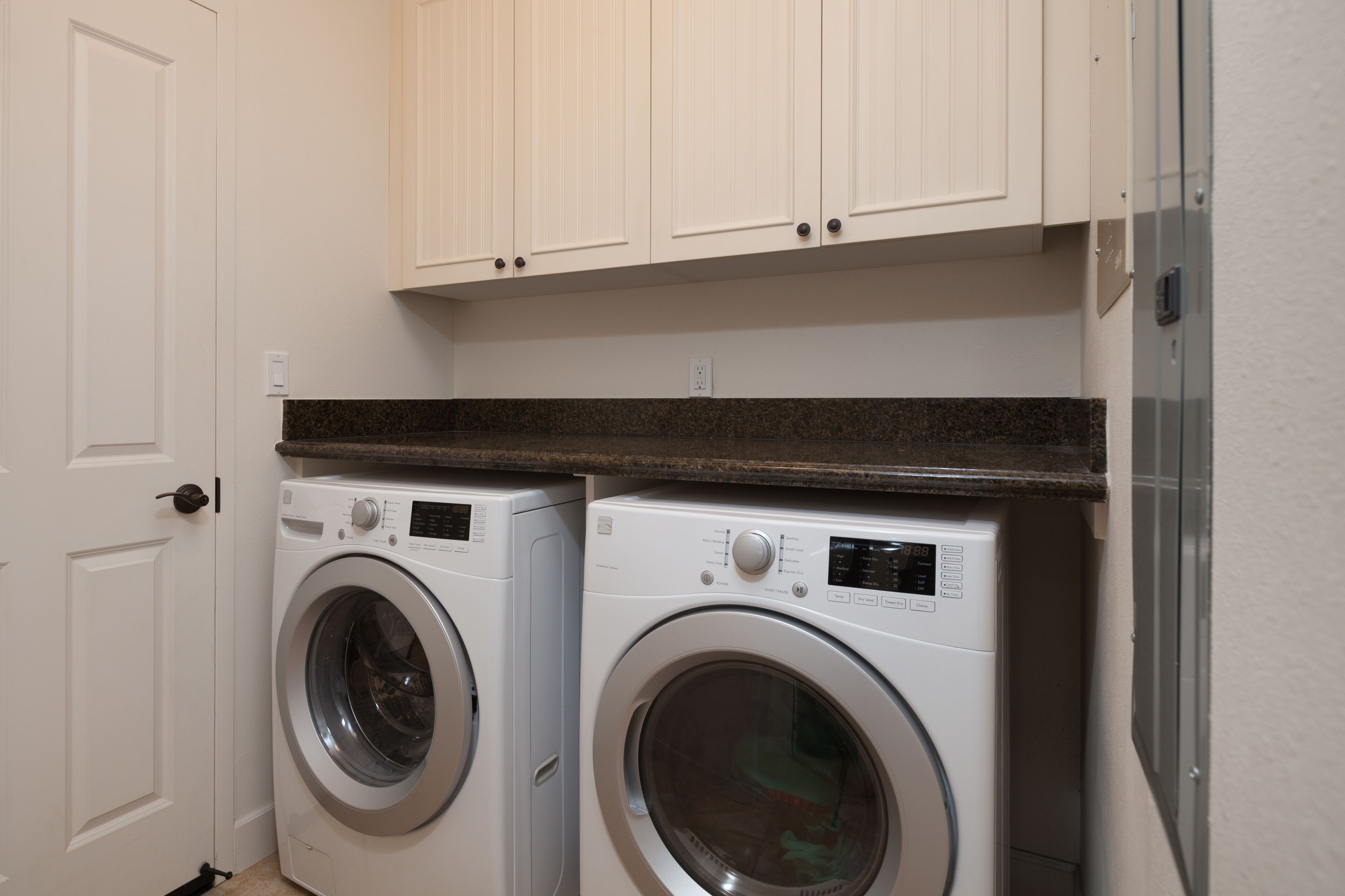 A laundry room with two front-loading washing machines and a countertop.